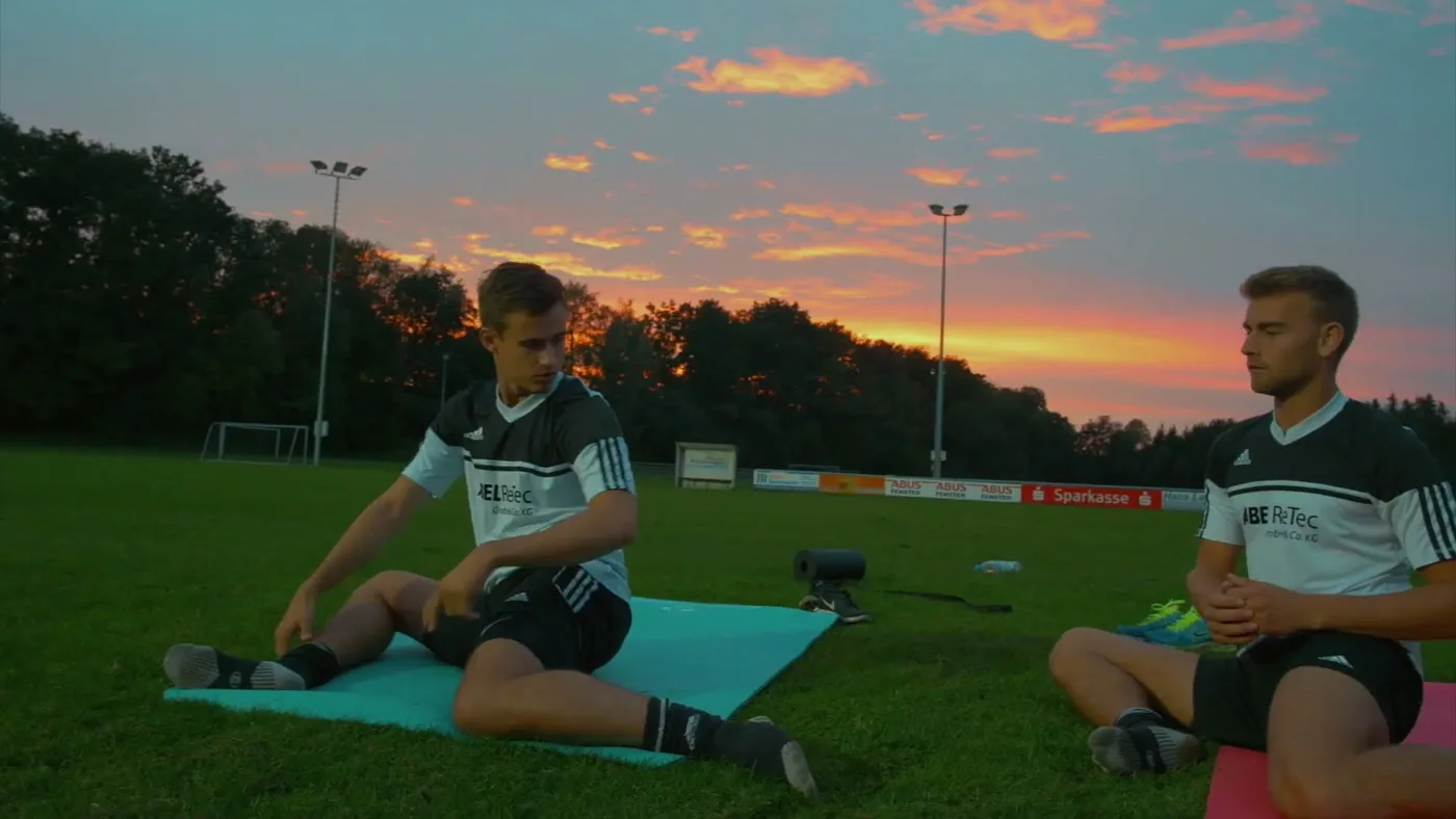 Spieler dehnen sich beim Workshop auf dem Platz bei Sonnenuntergang